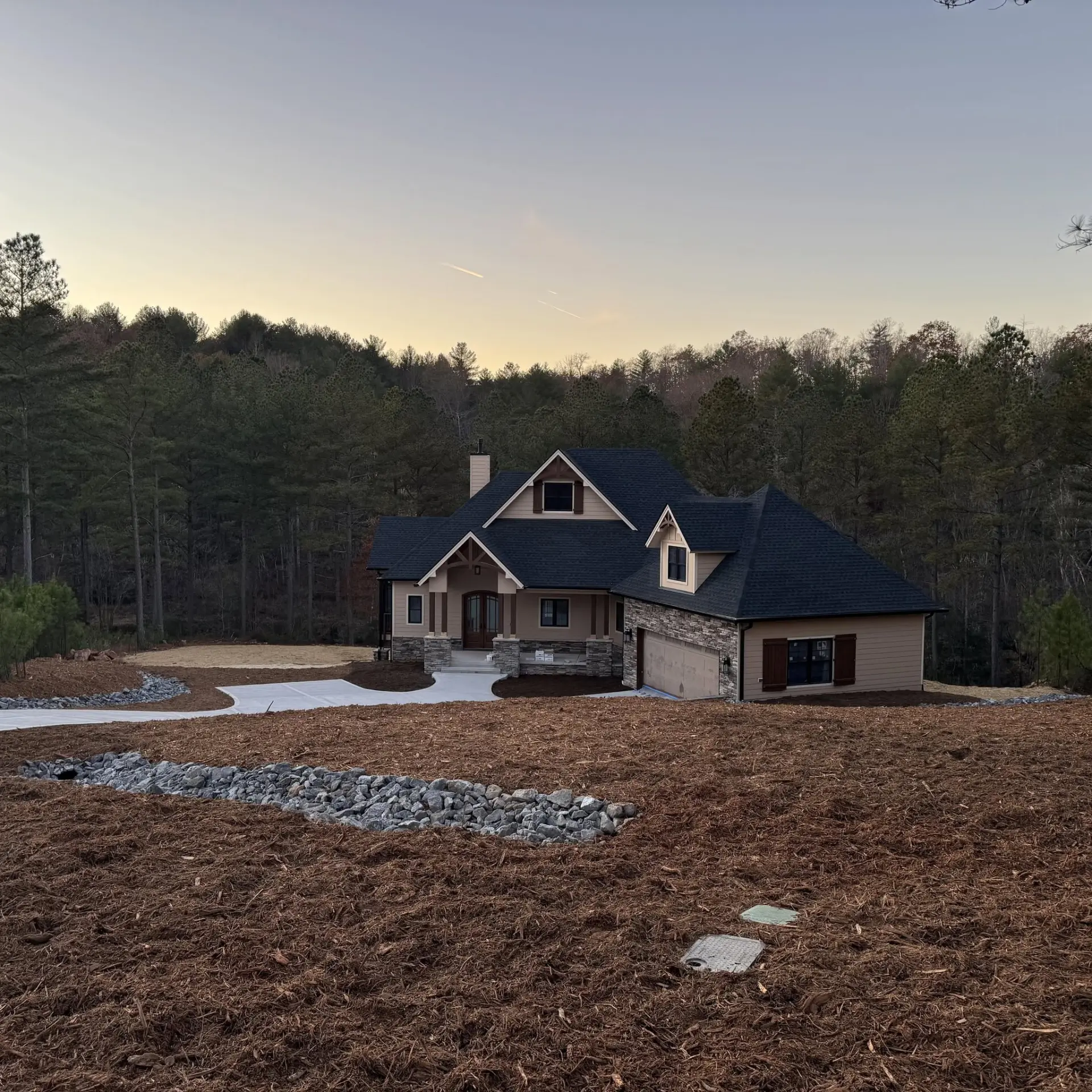 Finished home with fresh mulch beds, concrete drive and a rock drainage swale in Caldwell County, NC